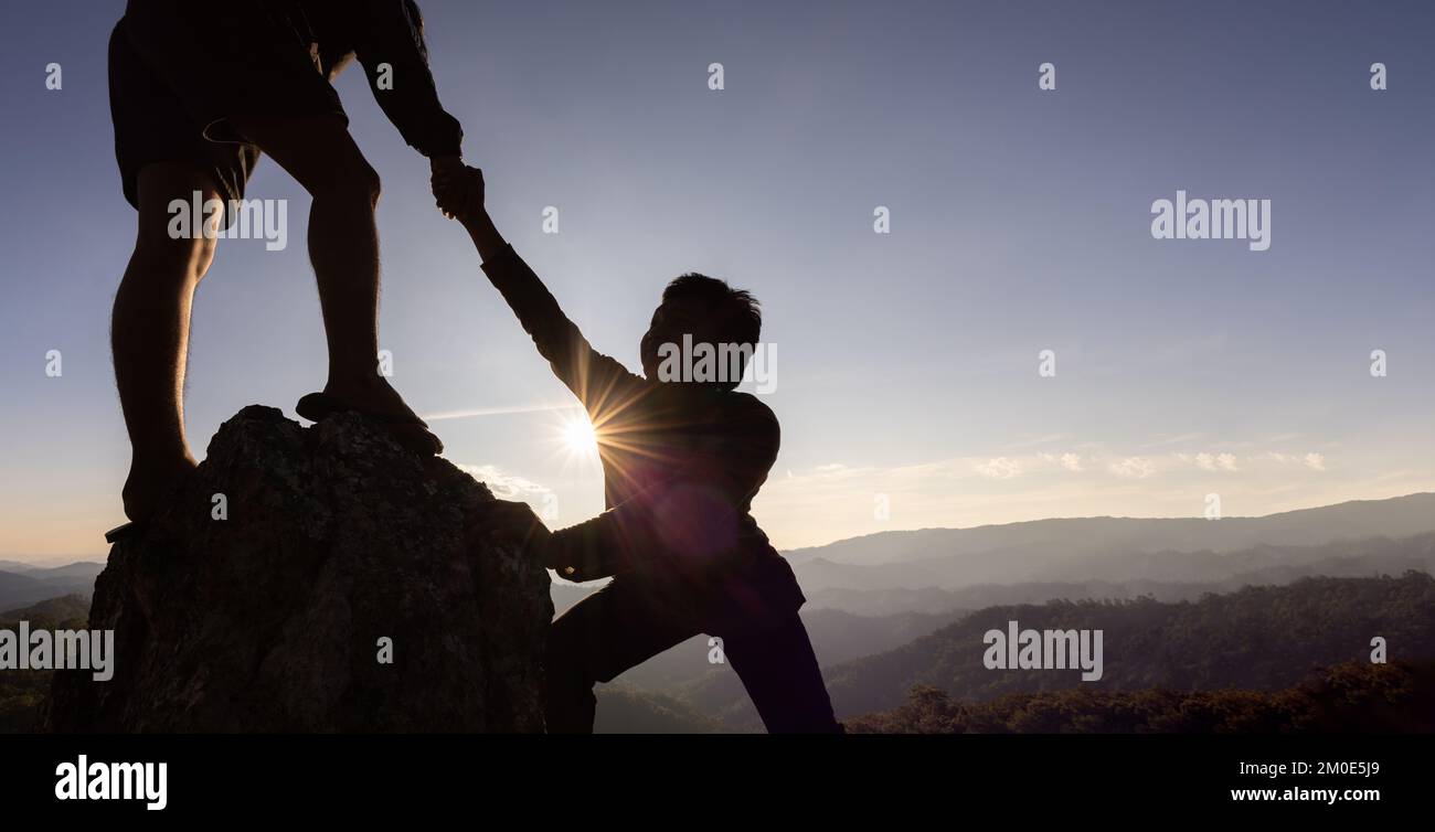 Silhouette de main d'aide entre deux grimpeurs. couple de randonnée aider les uns les autres silhouette dans les montagnes avec la lumière du soleil. Les hommes qui aident à tirer les gens vers le haut fr Banque D'Images