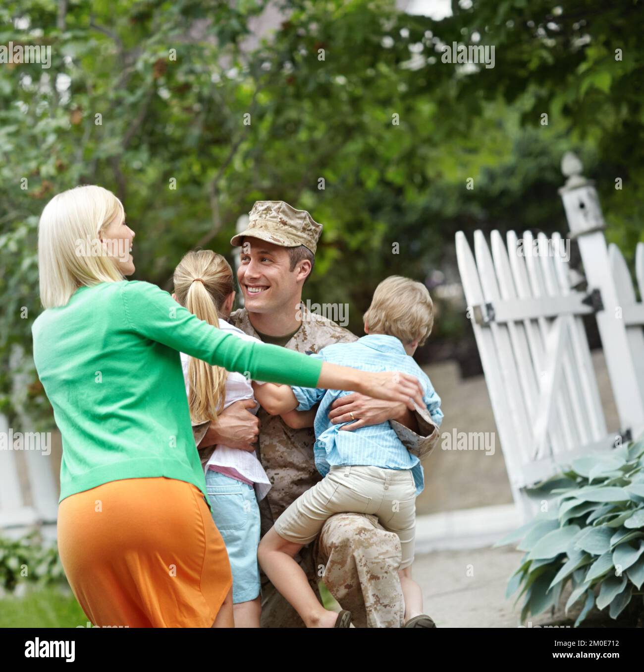 Bienvenue à la maison. Un père de l'armée étant accueilli par sa famille dans leur jardin. Banque D'Images
