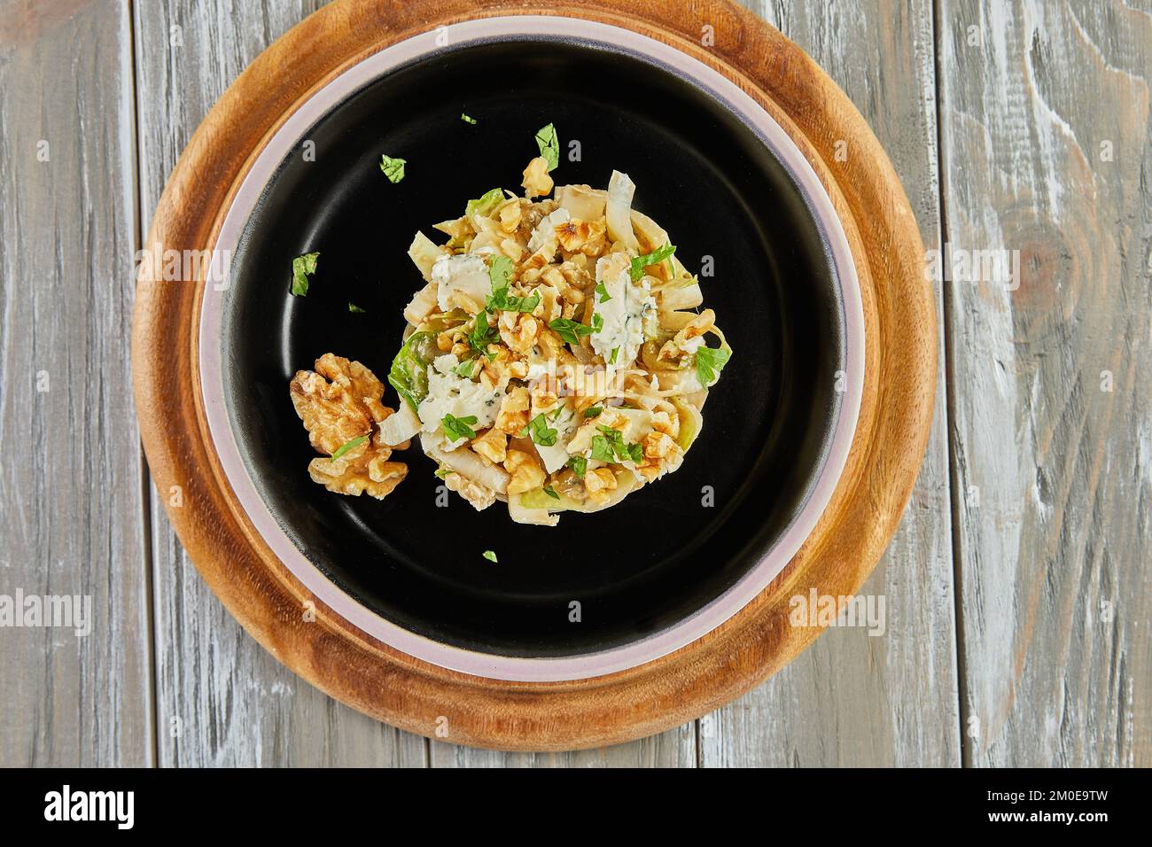 Salade de chicorée endive avec sauce Roquefort sur une assiette noire. Pose à plat. Banque D'Images