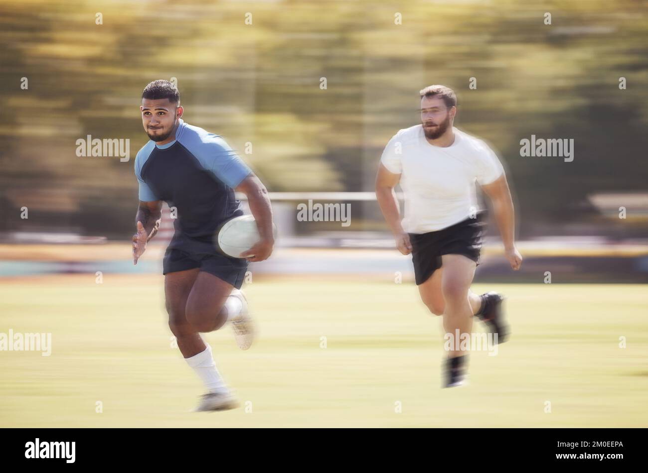 Un joueur de rugby de course mixte s'éloigne d'un adversaire tout en essayant de marquer un match de rugby à l'extérieur sur un terrain. Athlète hispanique masculine Banque D'Images