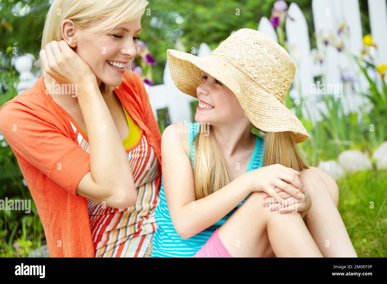 Profiter du soleil. Jolie petite fille assise sur l'herbe à l'extérieur avec sa mère. Banque D'Images