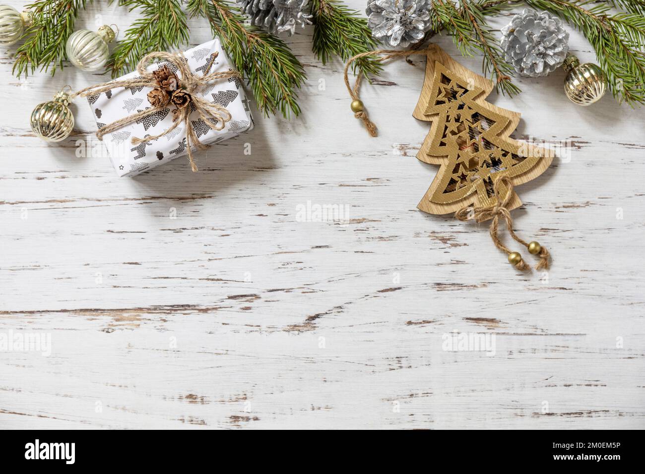 Décoration or de Noël, brindilles de sapin et boîte cadeau sur fond de bois blanc. Vue de dessus. Banque D'Images