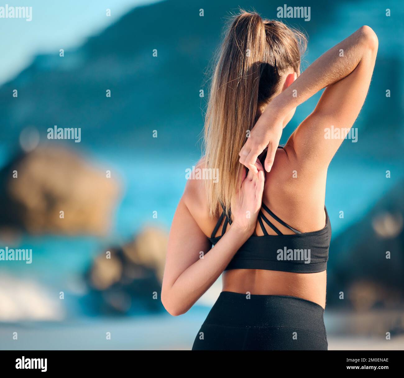Vision belle femme pratiquant l'exercice de yoga sur la plage. Jeune athlète féminine s'étirant et se réchauffant tout en faisant de l'entraînement à l'extérieur. Recherche Banque D'Images