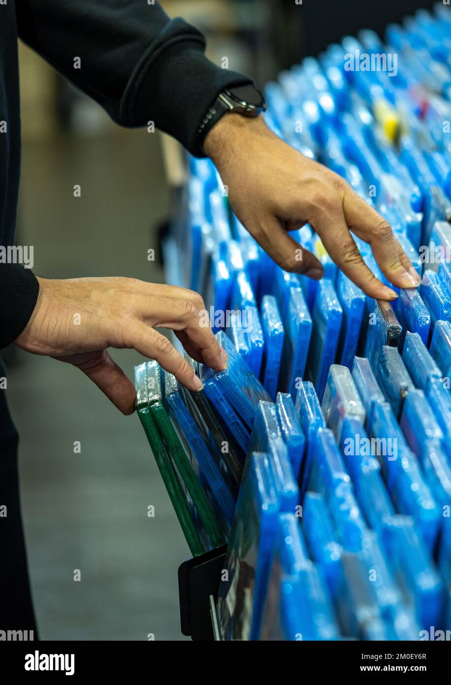 Les mains recherchant et choisissant des films et des dvd sur une étagère dans un magasin de collectionneur de film et la vente de marchandises de disques de film Banque D'Images