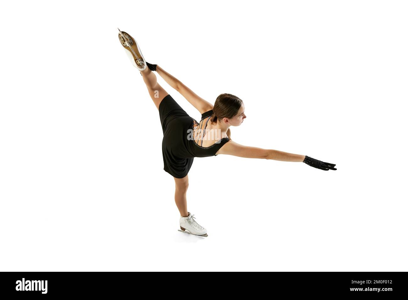 Portrait d'une jeune fille flexible, patineuse féminine en patinage de costume sur scène noire isolée sur fond blanc. Vue de dessus. Sport, beauté, hiver Banque D'Images