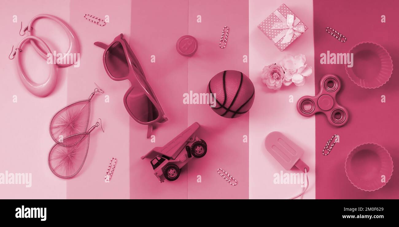 Composition pastel tendance avec boucles d'oreilles, lunettes de soleil, boîte à boissons, ballon de basket-ball, camion à jouets, boîte cadeau, crème glacée, fleur et spinner. Image tond en Viva Magenta, couleur de l'année 2023 Banque D'Images