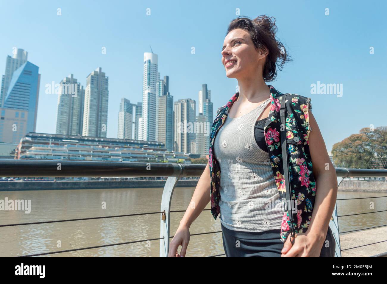 Femme heureuse d'adulte caucasien, est souriante et marche à travers la ville de Buenos Aires, avec des bâtiments dans l'arrière-plan et l'espace de copie. Banque D'Images