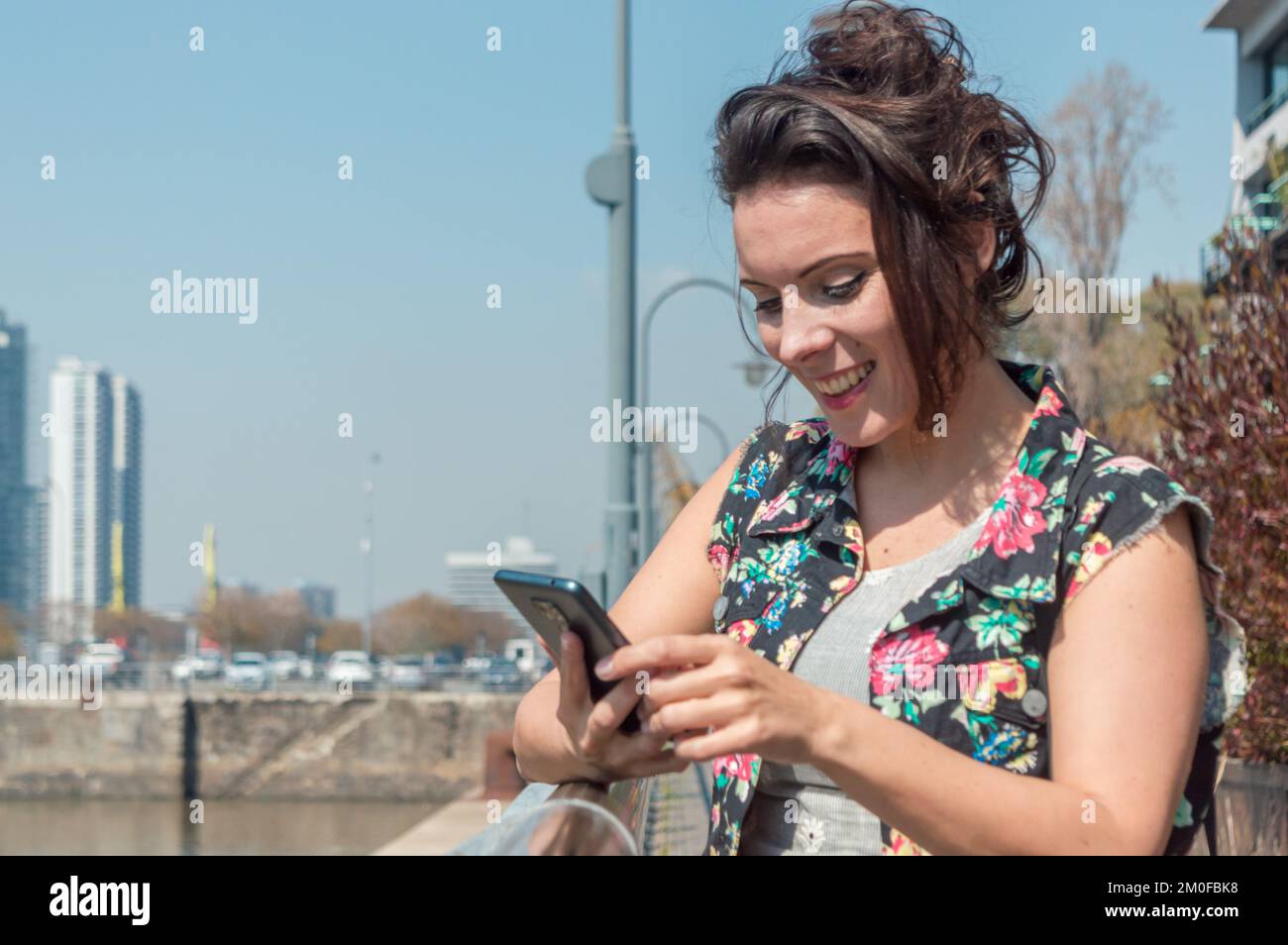 Femme adulte caucasienne debout souriant à l'extérieur vérifiant le téléphone à l'aide de la nouvelle application mobile, concept de technologie avec l'espace de copie. Banque D'Images