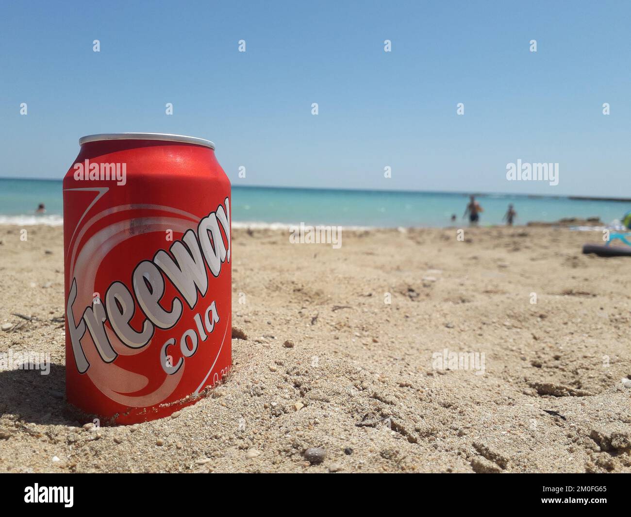 Une autoroute rouge de cola peut sur le sable d'une plage lors d'une journée ensoleillée à Vinaros Banque D'Images