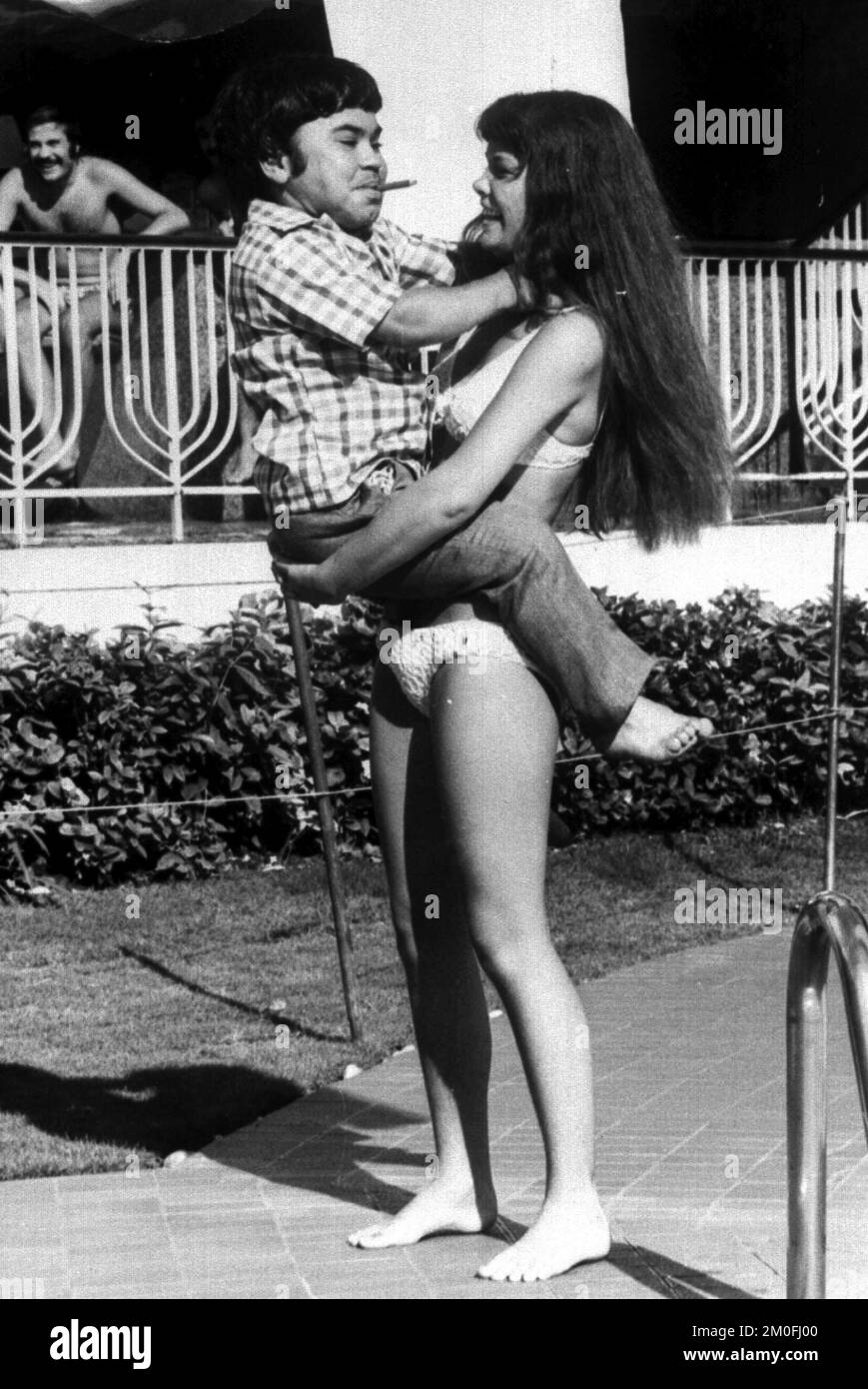 L'acteur français Herve Villechaize (à gauche) s'accroche à l'actrice danoise Janni Kristenson, lors d'une pause dans le tournage du film de James Bond « L'homme au pistolet d'or ». Banque D'Images