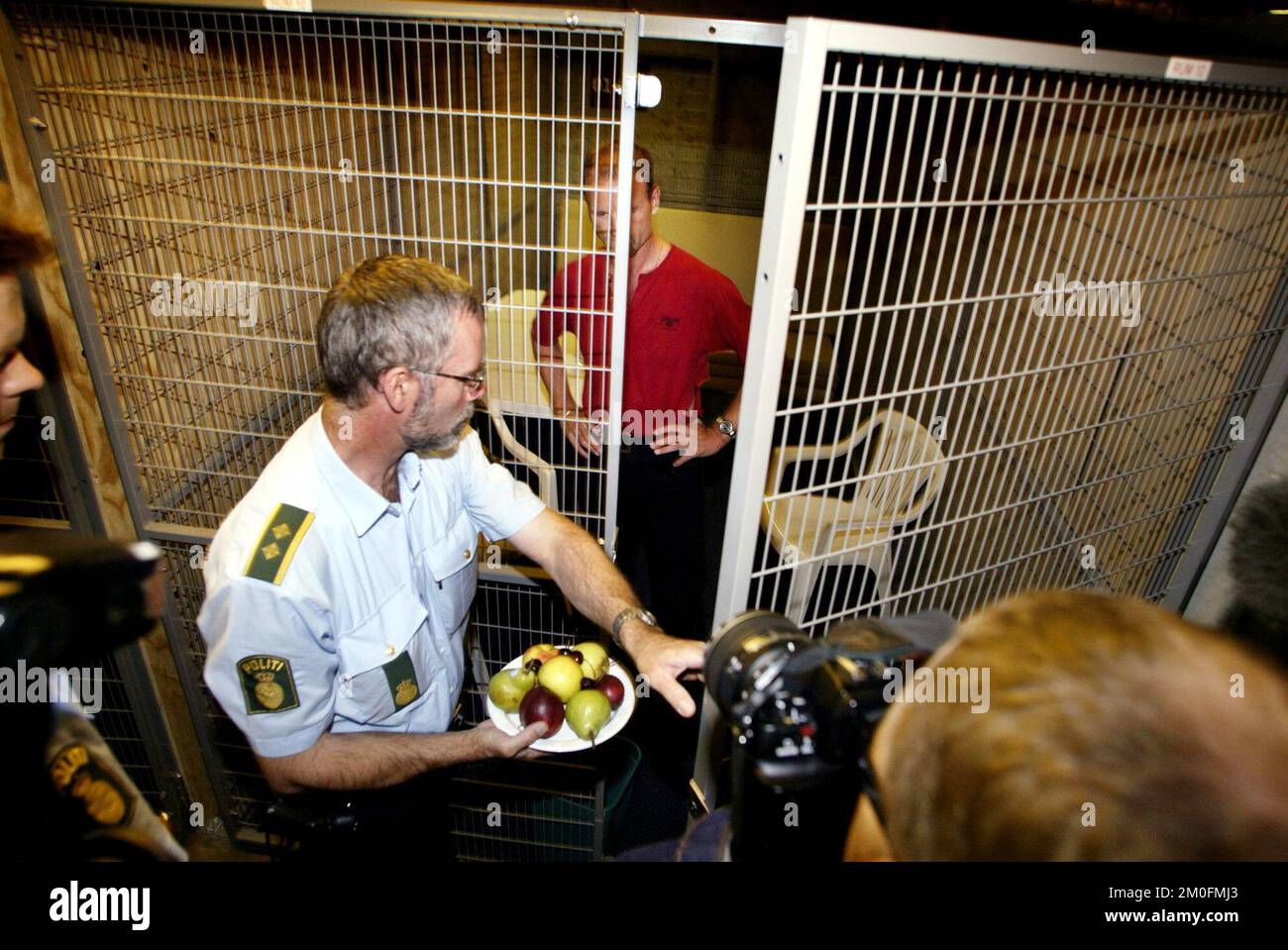 La présidence danoise de l'UE a débuté le 1er juillet. Les autorités danoises se préparent au grand nombre de réunions et de manifestations qui auront lieu au Danemark. La police de Copenhague a présenté ses cages ou "salles d'attente" pour les manifestants arrêtés. Le ministre des Affaires européennes Bertel Haarder a toutefois déclaré mardi que les réunions seraient dédramatisées. PHOTOS MONTRE : un policier sert des fruits (!) Pour un démonstrateur (MODÈLE) dans une des petites cages pour les manifestants détenus. *** DANEMARK SORTI *** photo : OLE Buntzen/POLFOTO-FAR Banque D'Images