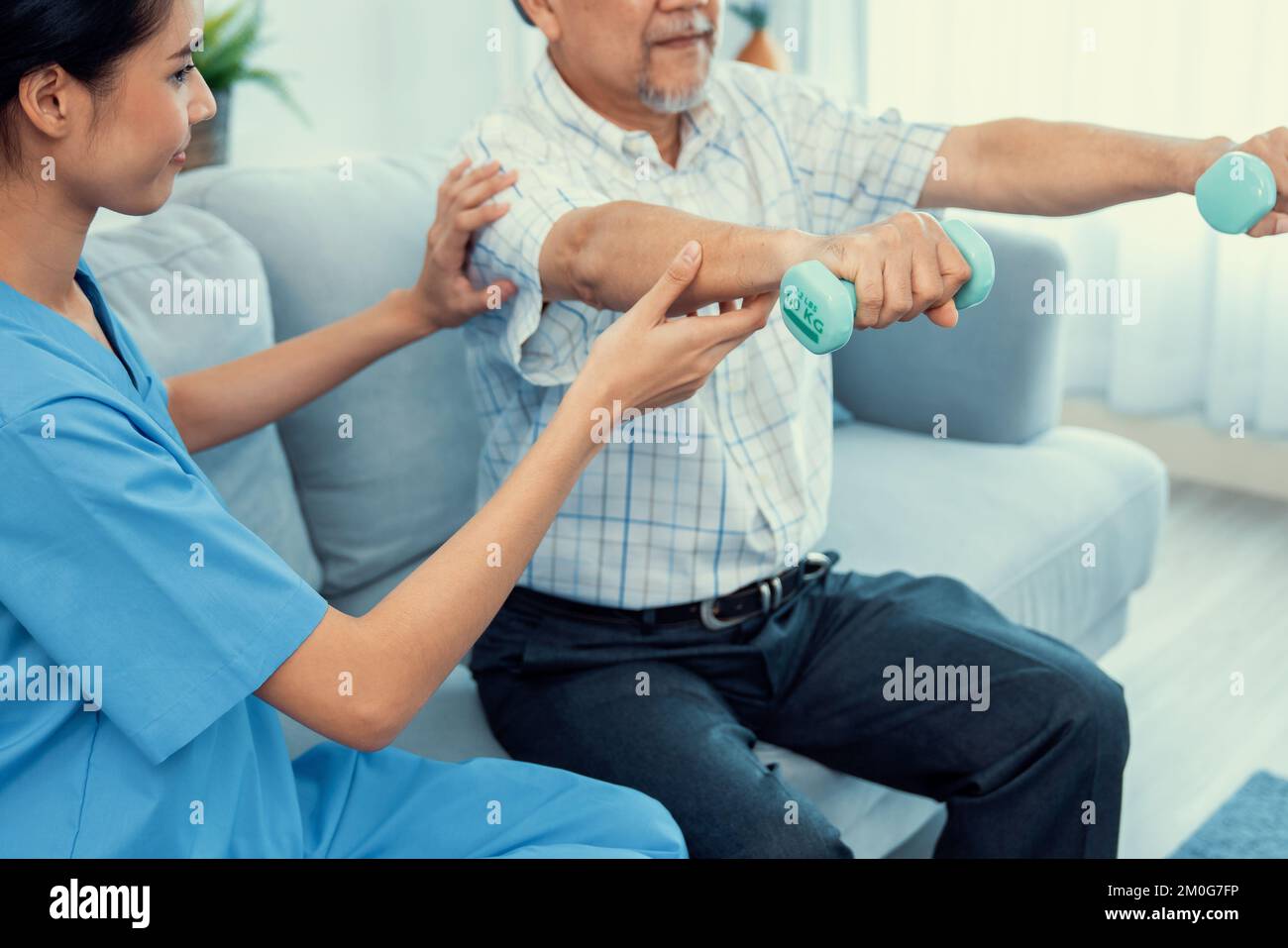 Un patient âgé ayant un niveau de satisfaction qui fait une thérapie physique avec l'aide de son soignant. Physiothérapie senior, traitement de physiothérapie, maison de soins pour le Banque D'Images