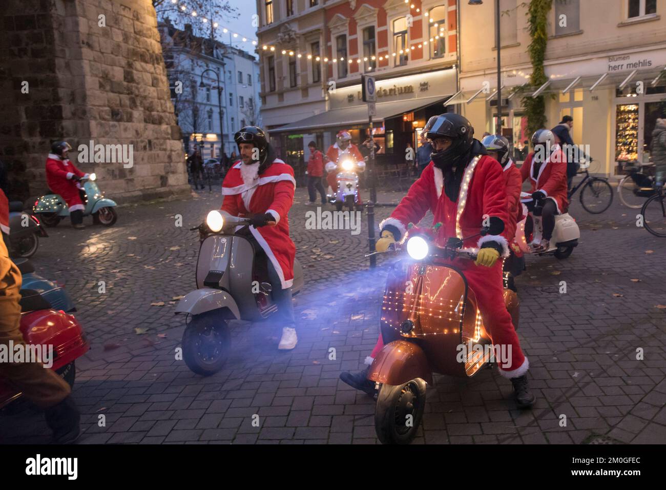 Les membres des clubs de scooter Vespa vêtus de Santas lors d'une promenade à travers la ville, Cologne, Allemagne. Les trottinettes sont illuminées et décorées pour le CHRI Banque D'Images
