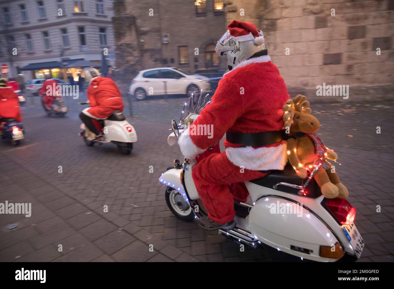 Les membres des clubs de scooter Vespa vêtus de Santas lors d'une promenade à travers la ville, Cologne, Allemagne. Les trottinettes sont illuminées et décorées pour le CHRI Banque D'Images