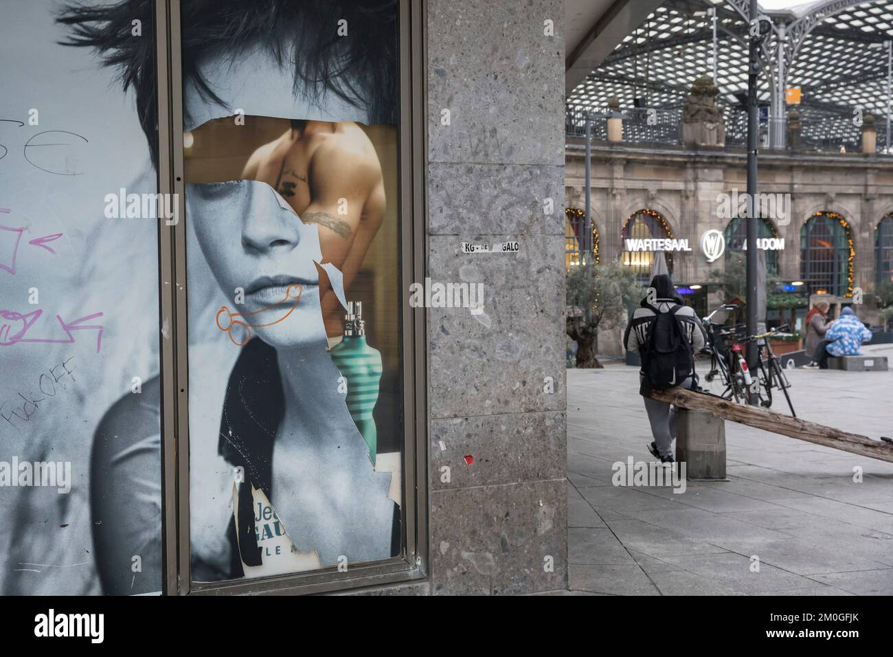 Graffiti sexiste sur une affiche publicitaire partiellement déchirée à la gare centrale de Cologne, Allemagne. Sexistisches graffitis auf einem teils abgerissenen W. Banque D'Images