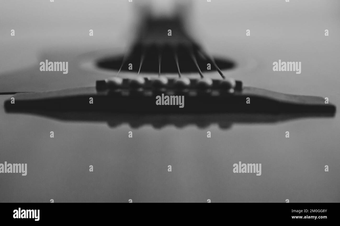 Un cliché en niveaux de gris de guitare acoustique floue vers le bas du tableau Banque D'Images