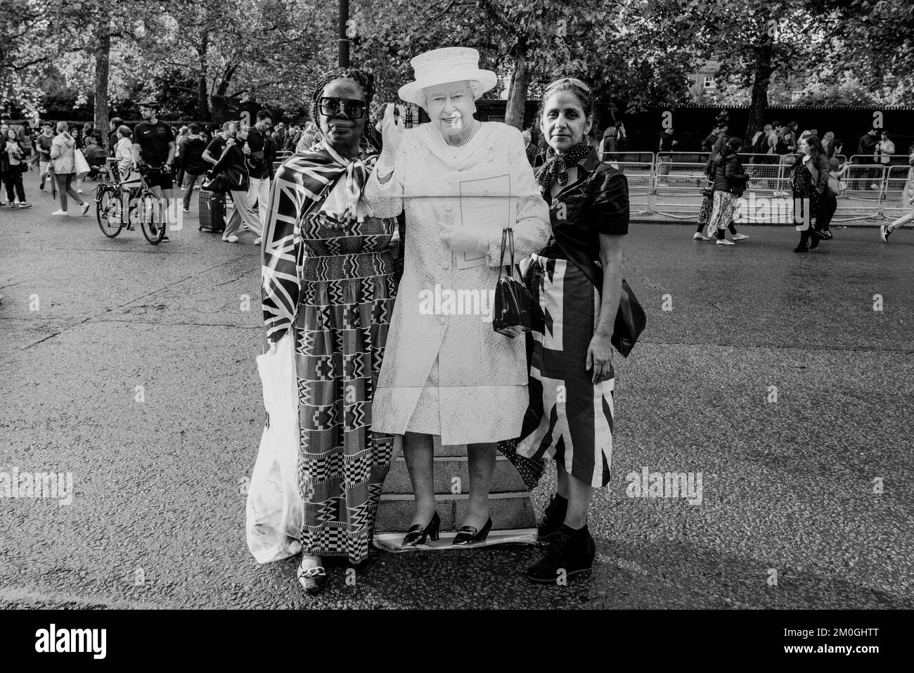 The Day After Queen Elizabeth II passe deux femmes Carry A Life Size carton Cut-out of the Queen in Tribute, The Mall, Londres, Royaume-Uni. Banque D'Images