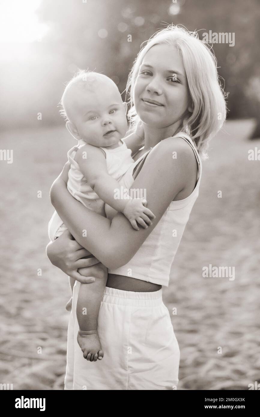 Une mère tient un bébé garçon heureux dans ses bras dans un parc d'été Banque D'Images