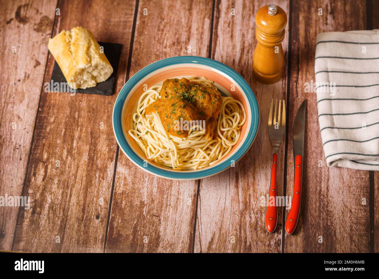 assiette de boulettes de viande à spaghetti avec couverts et saupoudreuse de pain et de poivre sur une table en bois Banque D'Images