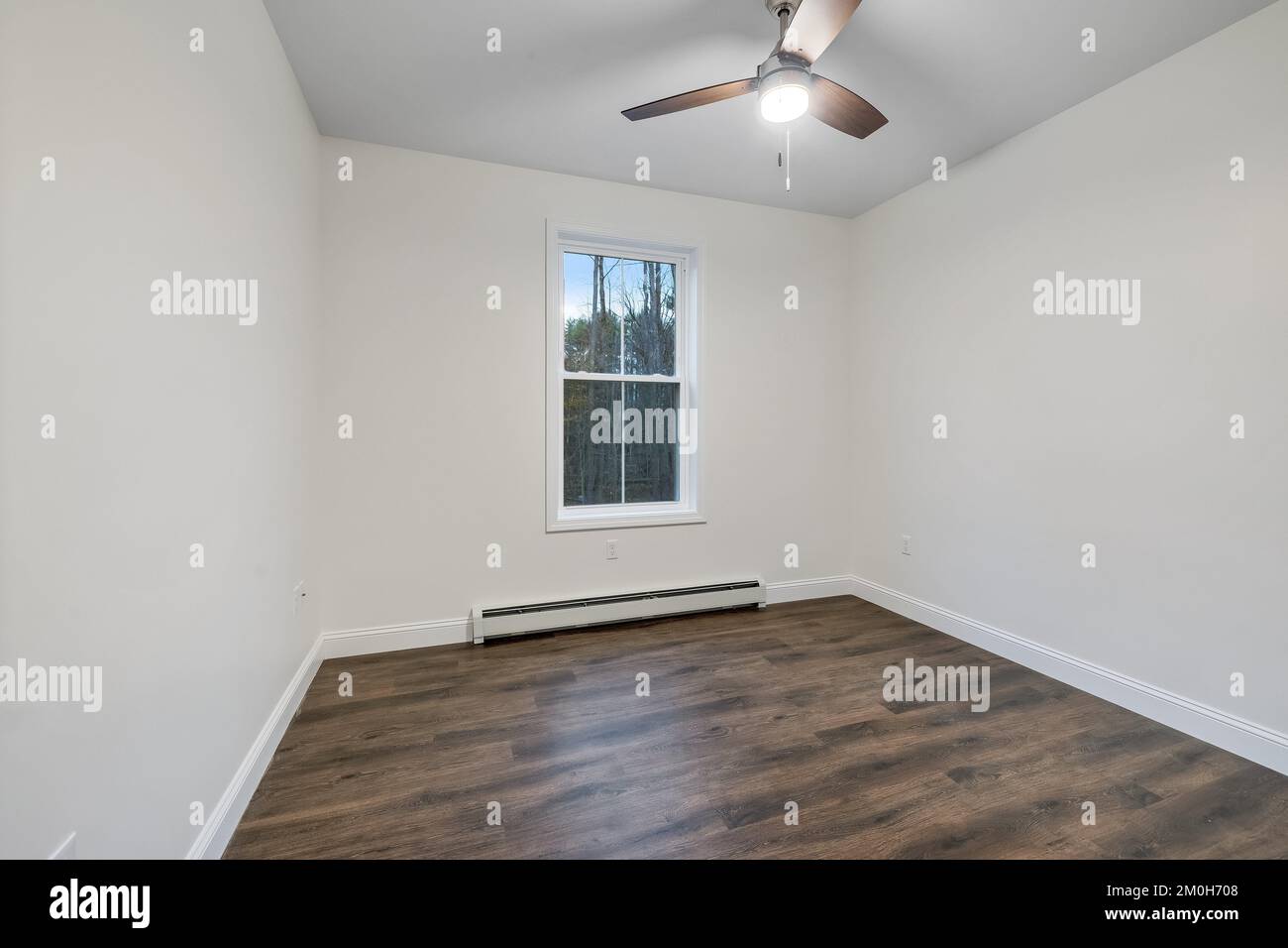 L'intérieur d'une chambre avec parquet, murs et fenêtres blancs et ventilateur de plafond Banque D'Images