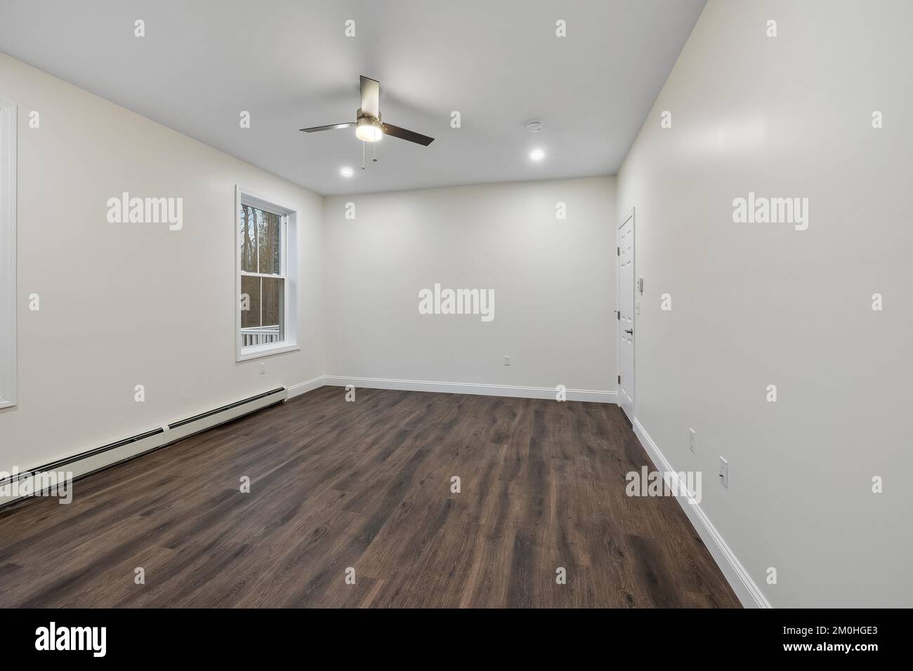 L'intérieur d'une pièce avec parquet, plinthe chauffante sur les murs blancs, ventilateur de plafond Banque D'Images