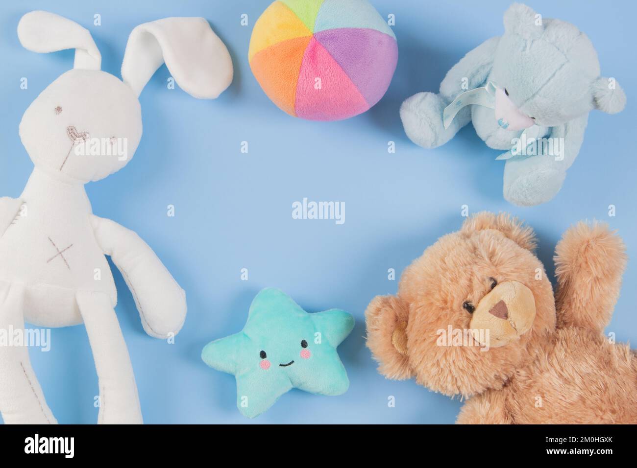 Collection de jouets Babby pour enfants. Ours en peluche colorés, lapin blanc et jouets en peluche sur fond bleu clair. Vue de dessus, espace de copie Banque D'Images