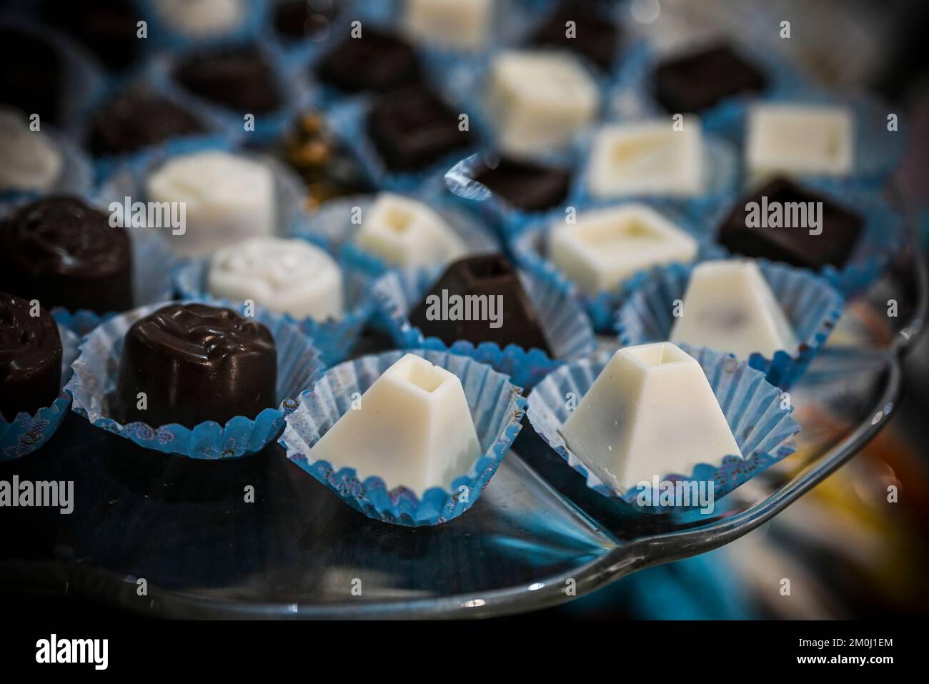 Assortiment de pralines au chocolat blanc et noir disposées sur une assiette en verre Banque D'Images