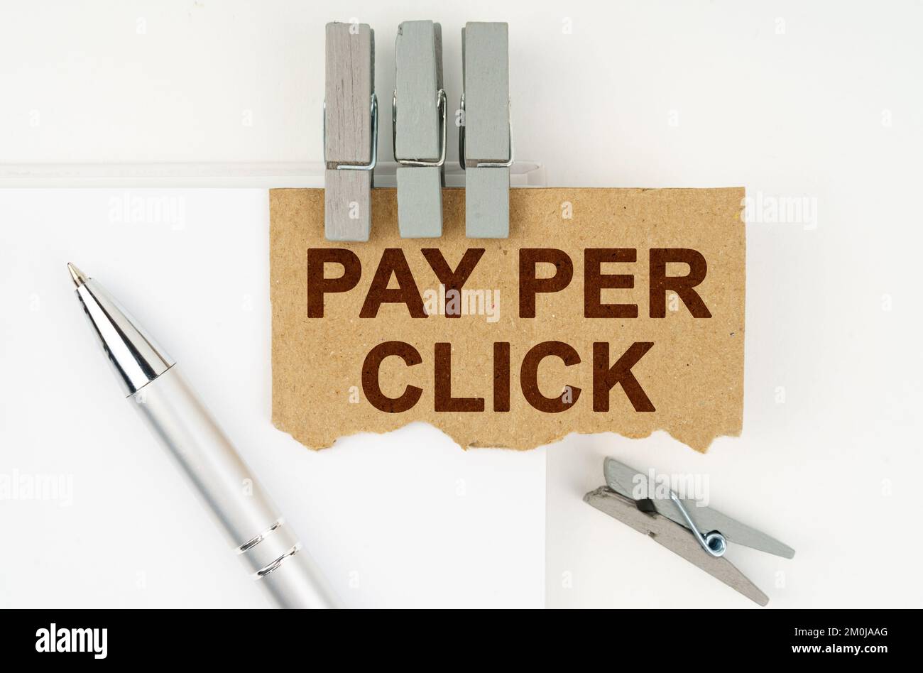 Concept commercial et financier. Sur fond blanc se trouve un carnet, un stylo, des épingles à linge et du carton avec l'inscription - payer par clic Banque D'Images