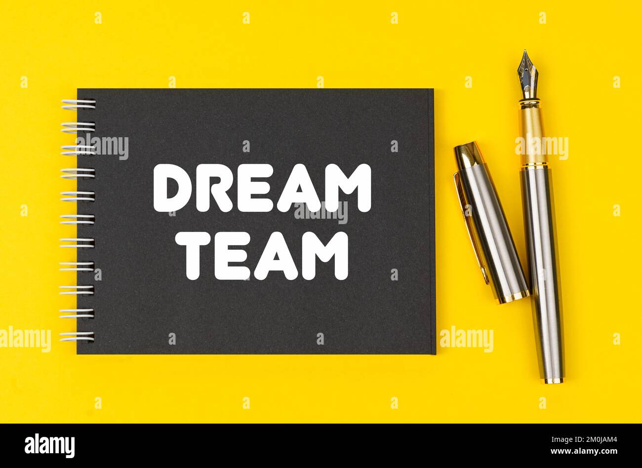 Concept commercial et financier. Sur un fond jaune se trouve un stylo et un bloc-notes noir avec l'inscription - Dream Team Banque D'Images