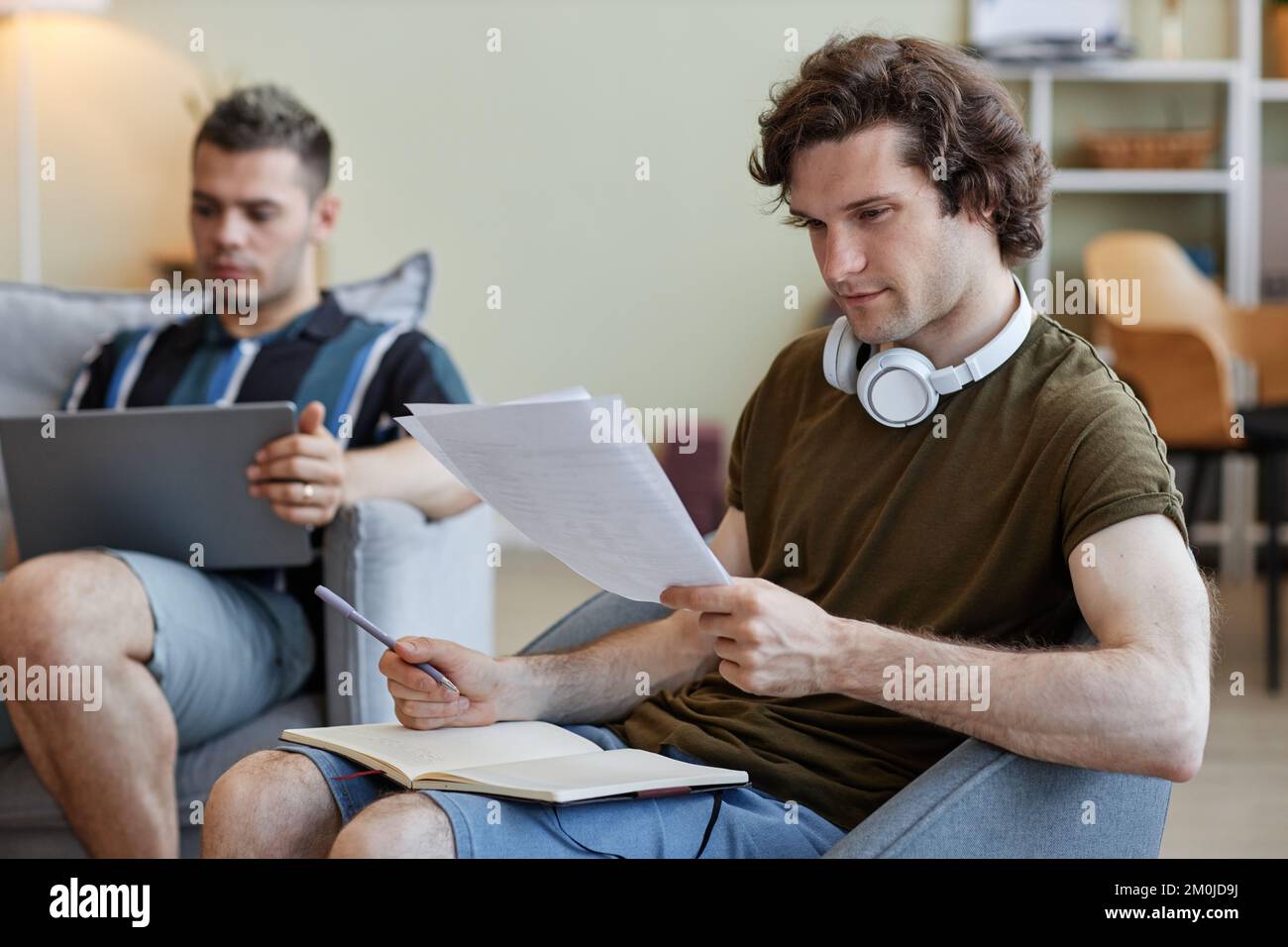 Portrait de deux colocataires vivant ensemble, se concentrer sur le jeune homme étudiant ou se préparant aux examens en premier plan Banque D'Images