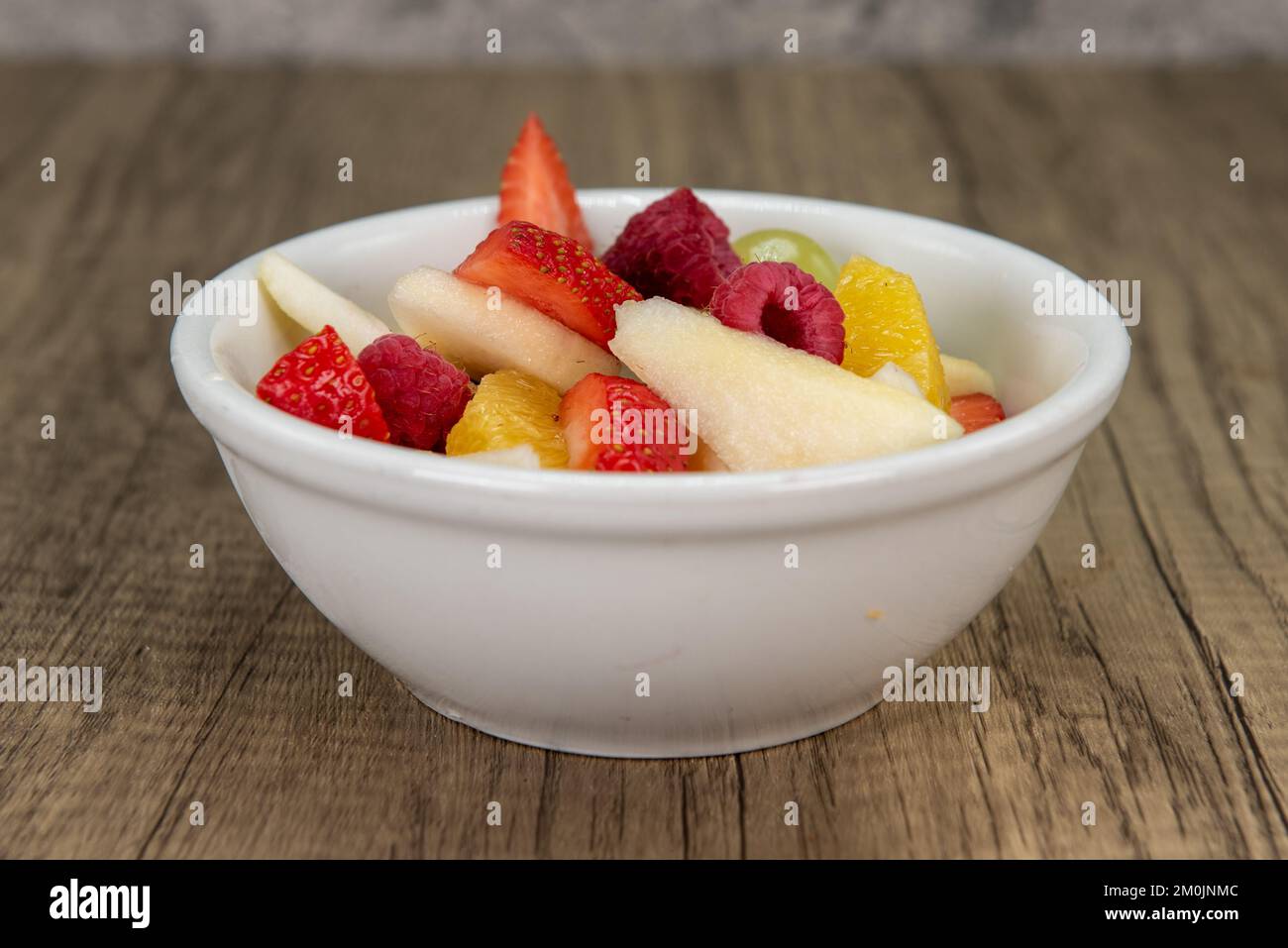 Grand bol de fruits frais en tranches, y compris fraise, poire et orange. Banque D'Images