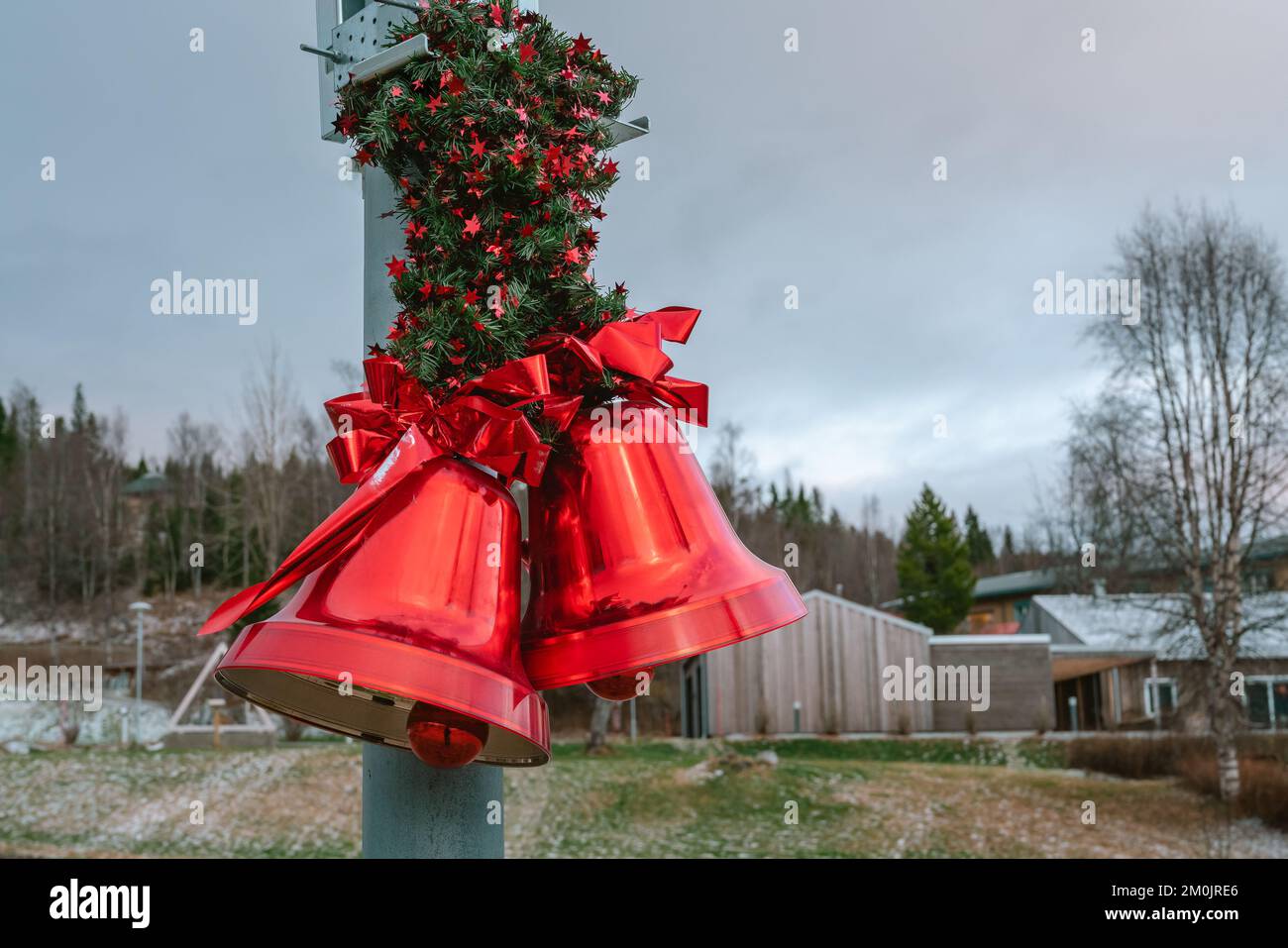 Deux grands cloches rouges de Noël avec noeud rouge et feuilles de pin, décoration de Noël de rue, arrière-plan flou Banque D'Images