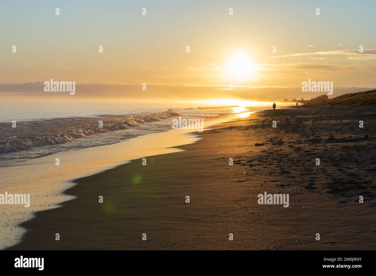 Plage de Papamoa au soleil du matin marcheurs matinaux non reconnaissables dans la silhouette. Banque D'Images