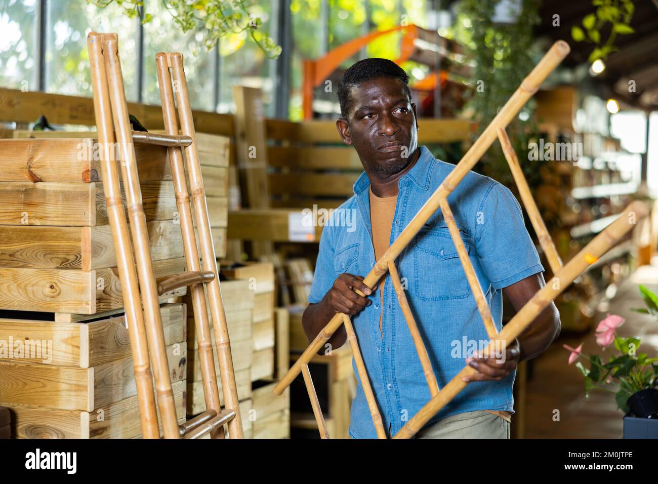Afro-américain à la recherche d'un escabeau en bambou décoratif dans une boutique de jardinage Banque D'Images
