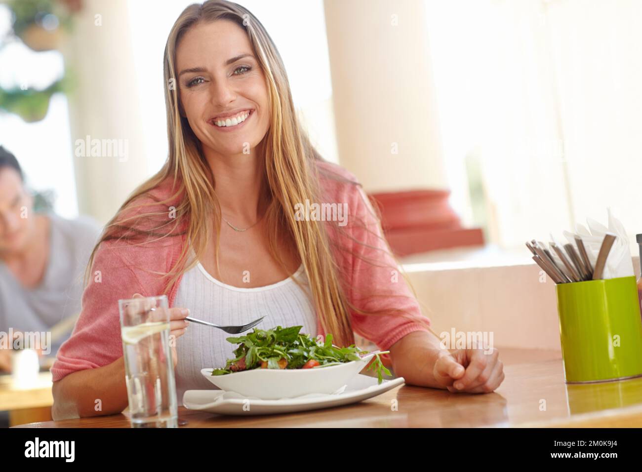 Rien n'est plus unique... une salade fraîche. Une belle jeune femme assise dans un restaurant et savourant une salade saine. Banque D'Images