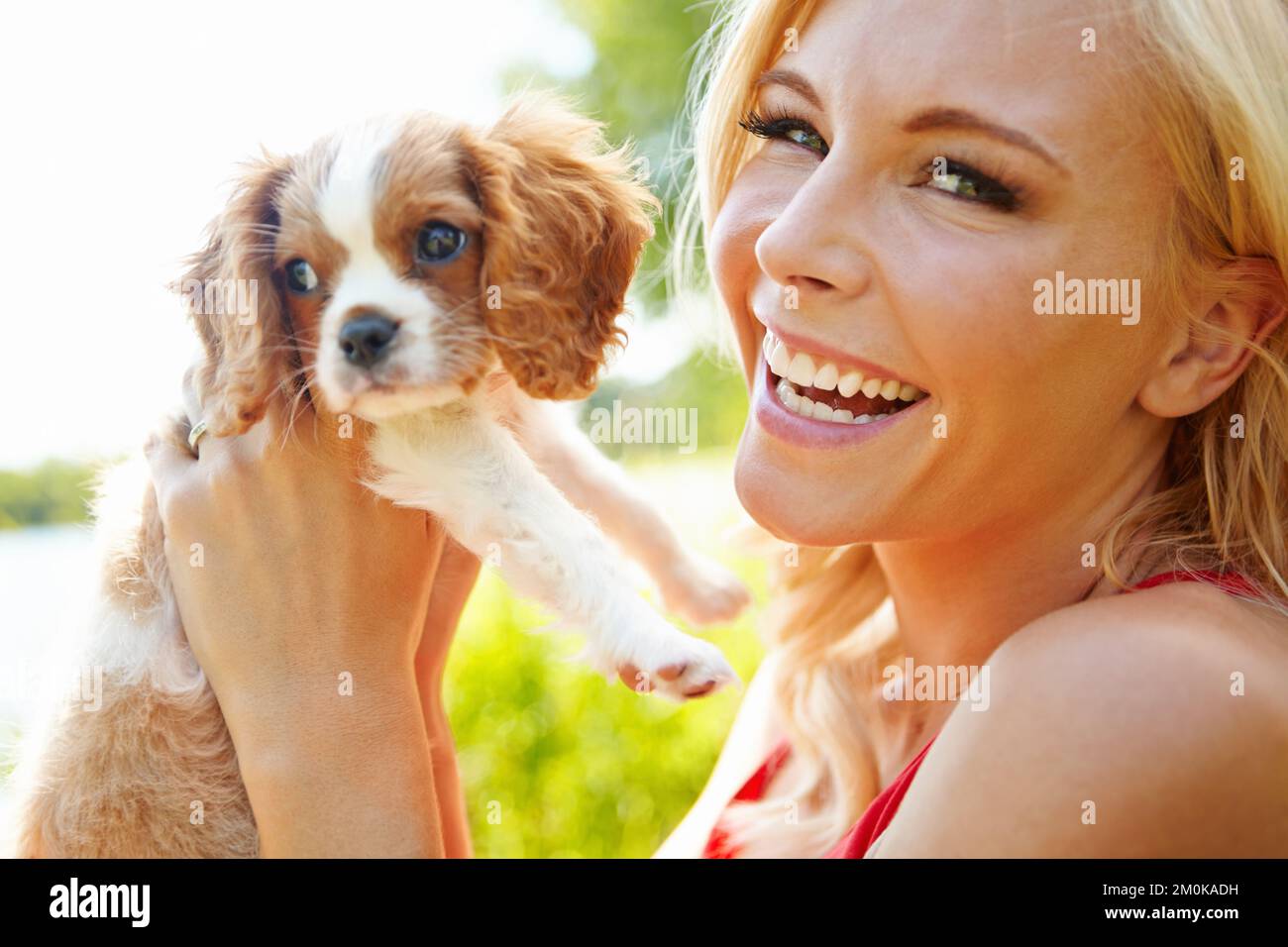 Trop mignon pour les mots. Portrait d'une belle blonde heureuse tenant un chiot adorable à l'extérieur. Banque D'Images