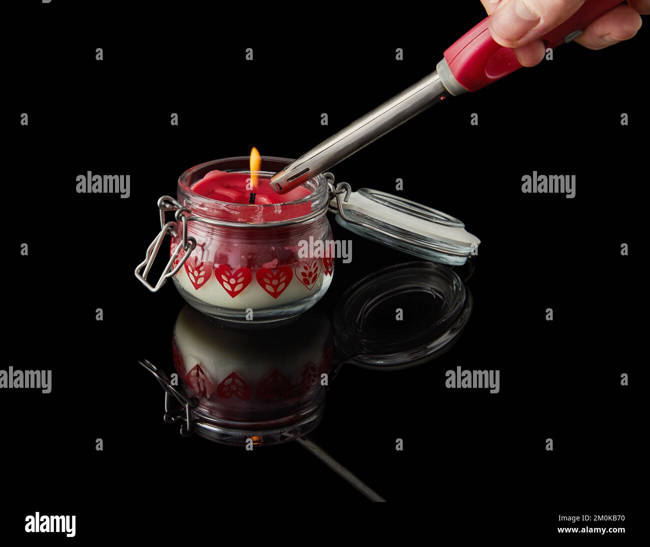 Bougie lumineuse sur fond noir avec des arômes de vanille, de cerise, de grenade et de noix de coco. Banque D'Images