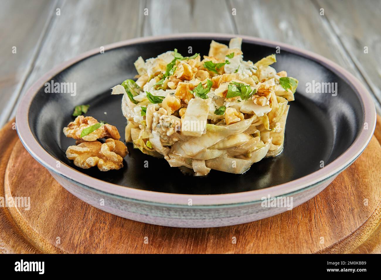 Salade de chicorée endive avec sauce Roquefort sur une assiette noire. Pose à plat. Banque D'Images