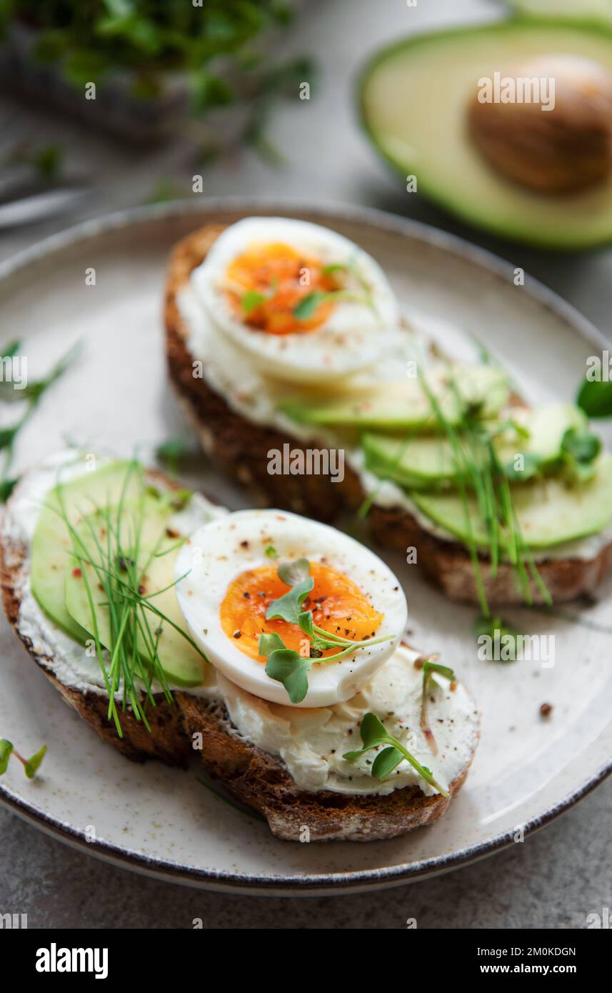 Pain grillé, œufs durs, tranche d'avocat, micro-légumes sur une assiette, heure du petit déjeuner Banque D'Images