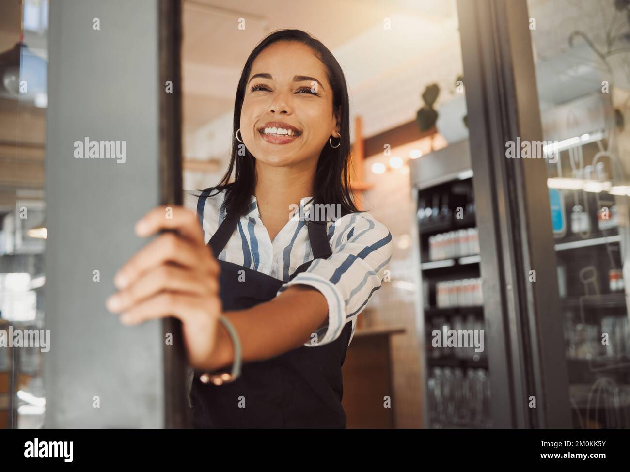 Le propriétaire de l'entreprise attend les clients à l'entrée de son magasin. Jeune femme d'affaires debout à la porte de son café. Bon patron dans l'épicerie Banque D'Images