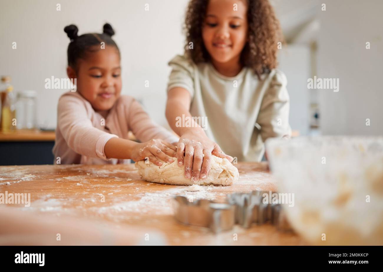 Deux sœurs de race mixte se sont amusées tout en cuisant ensemble à la maison. Les enfants ne sont joueurs que lorsqu'ils apprennent à cuisiner dans une cuisine Banque D'Images