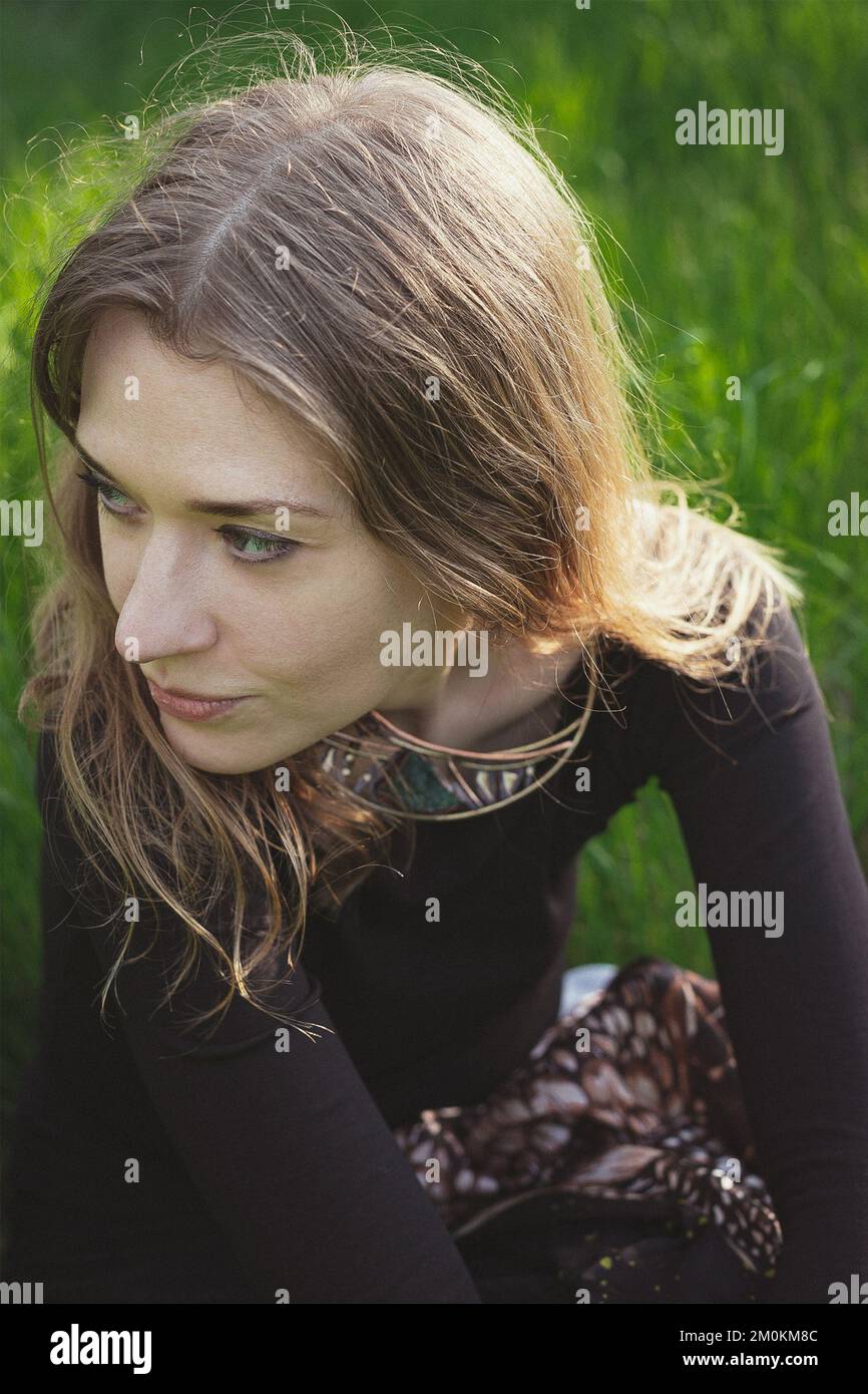 Femme en gros plan regardant loin et assis sur une photo de portrait d'herbe Banque D'Images