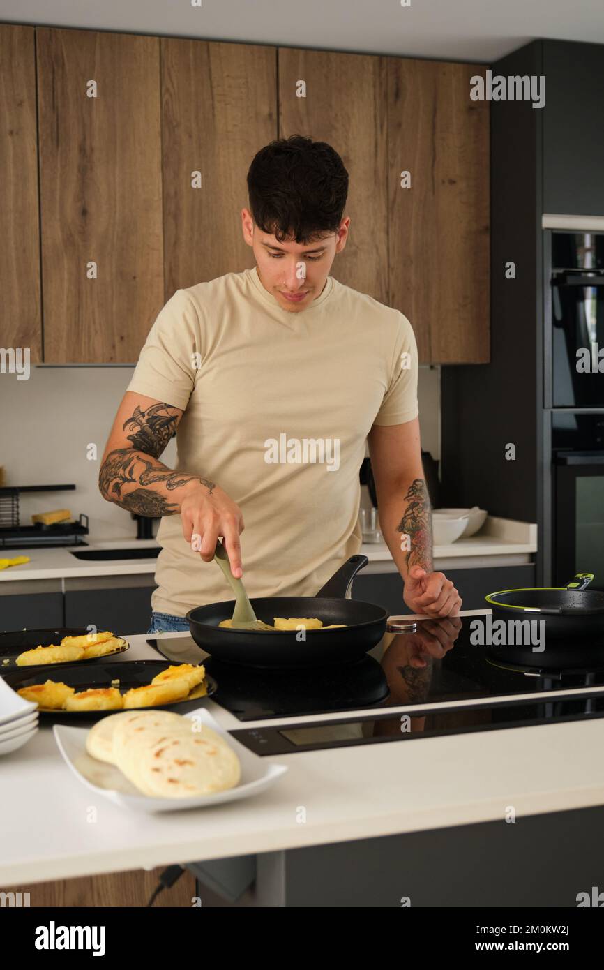 Jeune homme équatorien cuisant des lapingachos dans une casserole. Banque D'Images