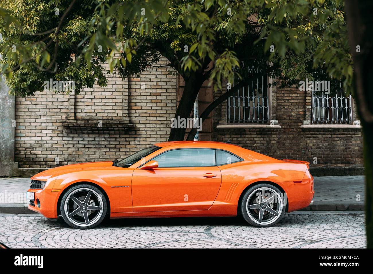 Voiture Orange Chevrolet Camaro garée dans la rue. Sixième génération Banque D'Images