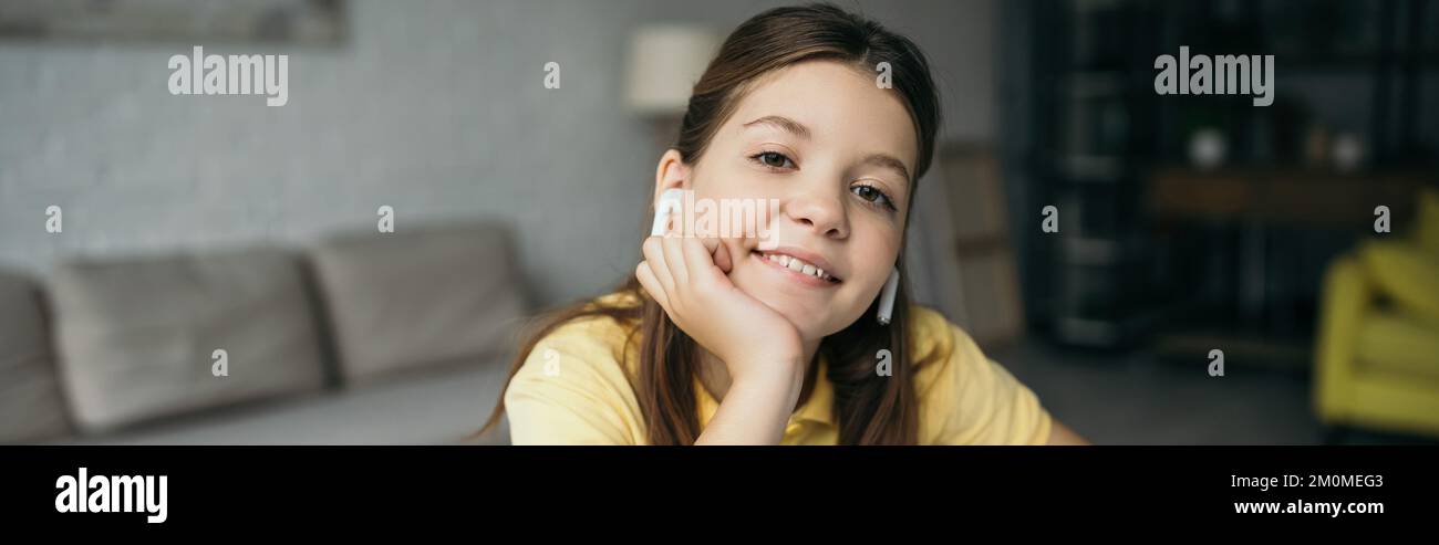 portrait d'une fille heureuse dans des écouteurs sans fil écoutant de la musique à la maison, bannière Banque D'Images