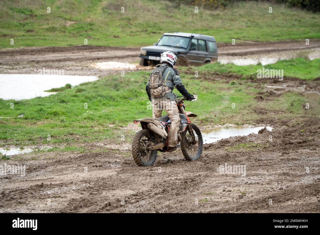 Motocycliste qui fait un vélo tout-terrain sur des terrains boueux et aquatiques, Wiltshire, Royaume-Uni Banque D'Images