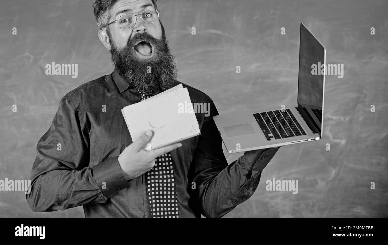Choisissez la bonne méthode d'apprentissage. Enseignant choisissant l'approche moderne de l'enseignement. Un hipster barbu pour enseignants tient un livre et un ordinateur portable. Les technologies modernes en bénéficient Banque D'Images