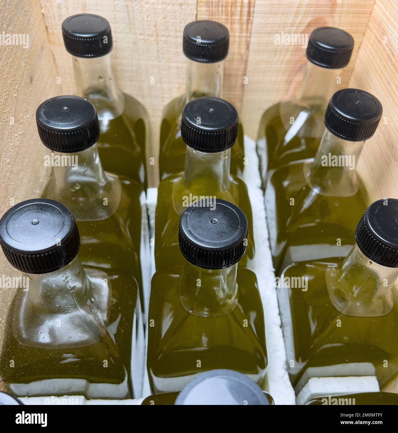 Bouteilles d'huile d'olive en verre côte à côte dans une caisse en bois. Huile d'olive en bouteille de verre. Banque D'Images