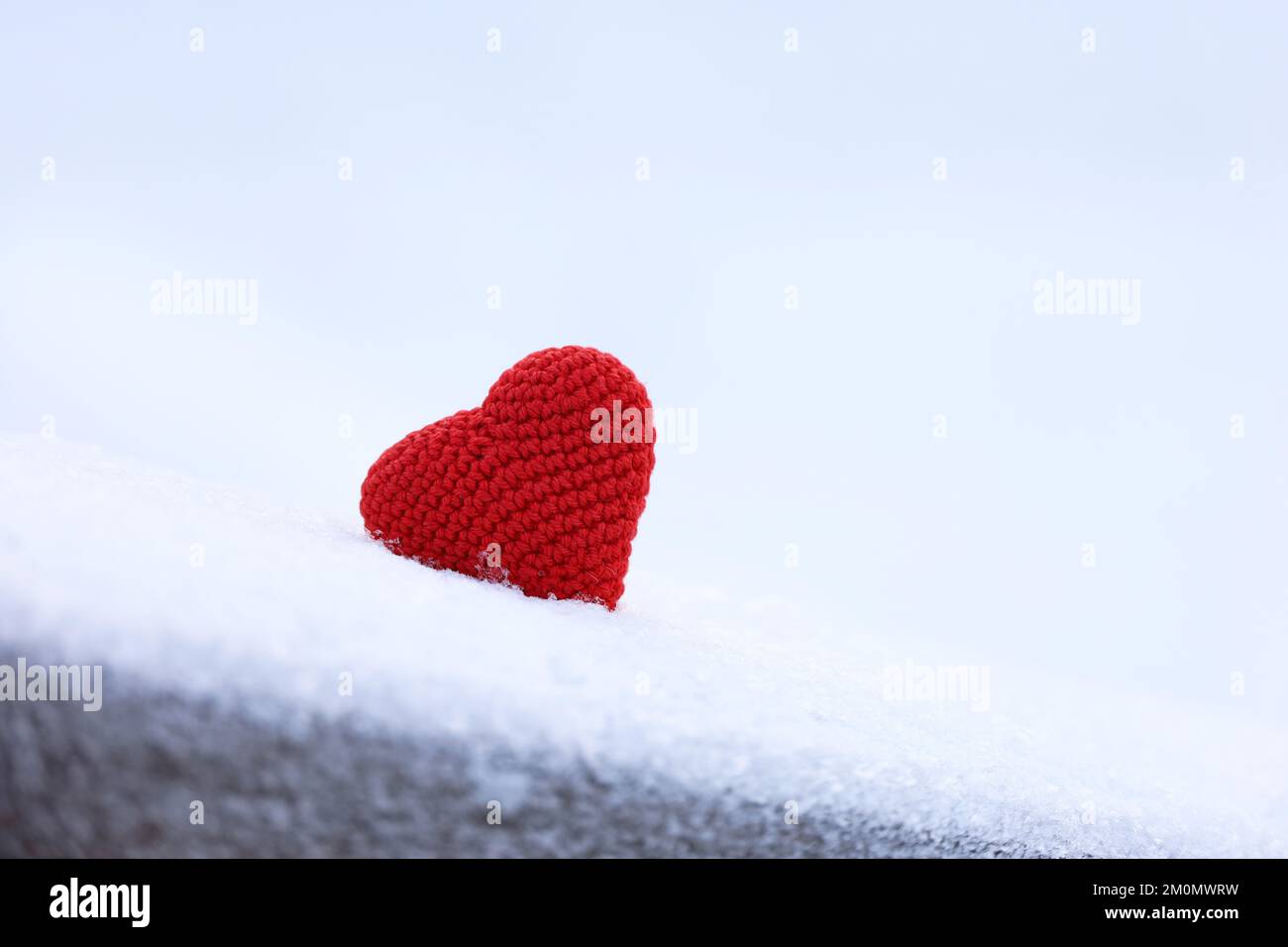 Coeur d'amour en maille dans la neige, carte de Saint-Valentin. Toile de fond pour un événement romantique, une fête de Noël ou le temps d'hiver Banque D'Images