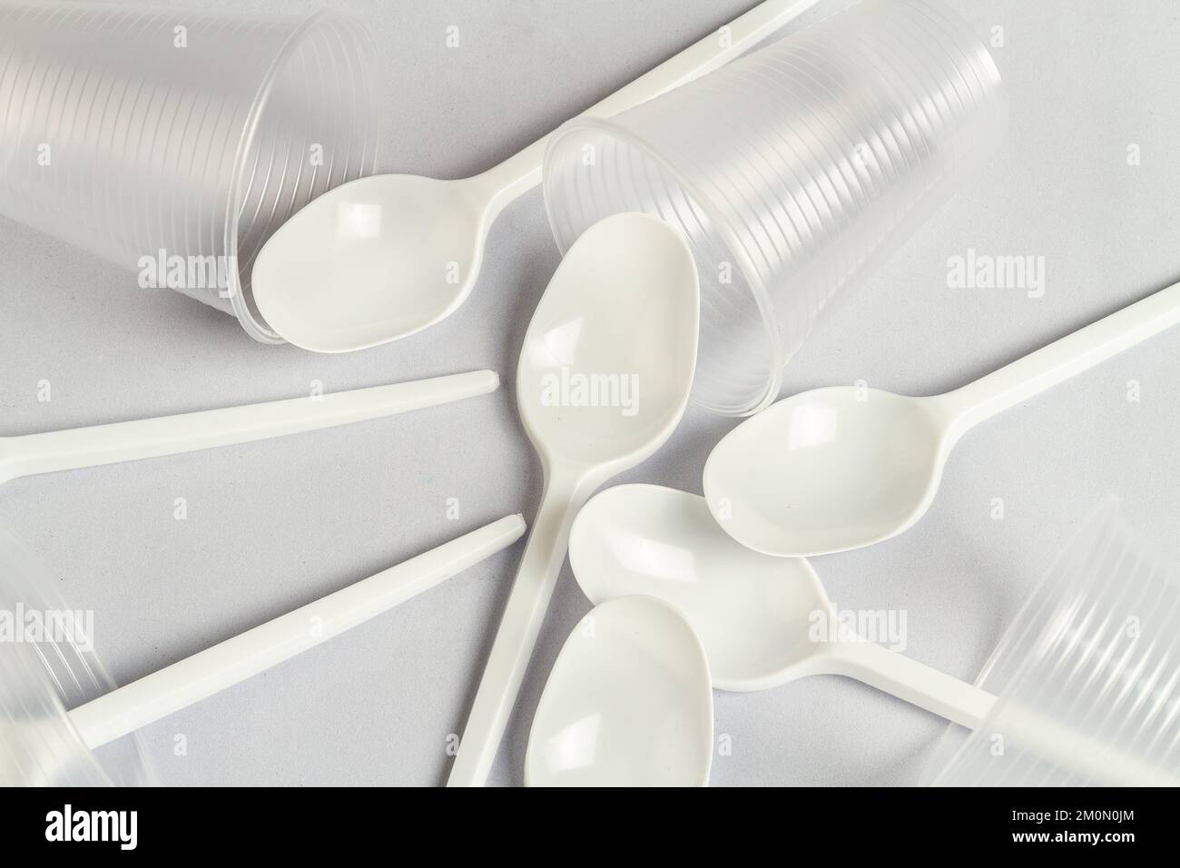 Cuillères et tasses en plastique jetables sur blanc. Gros plan des ustensiles. Banque D'Images